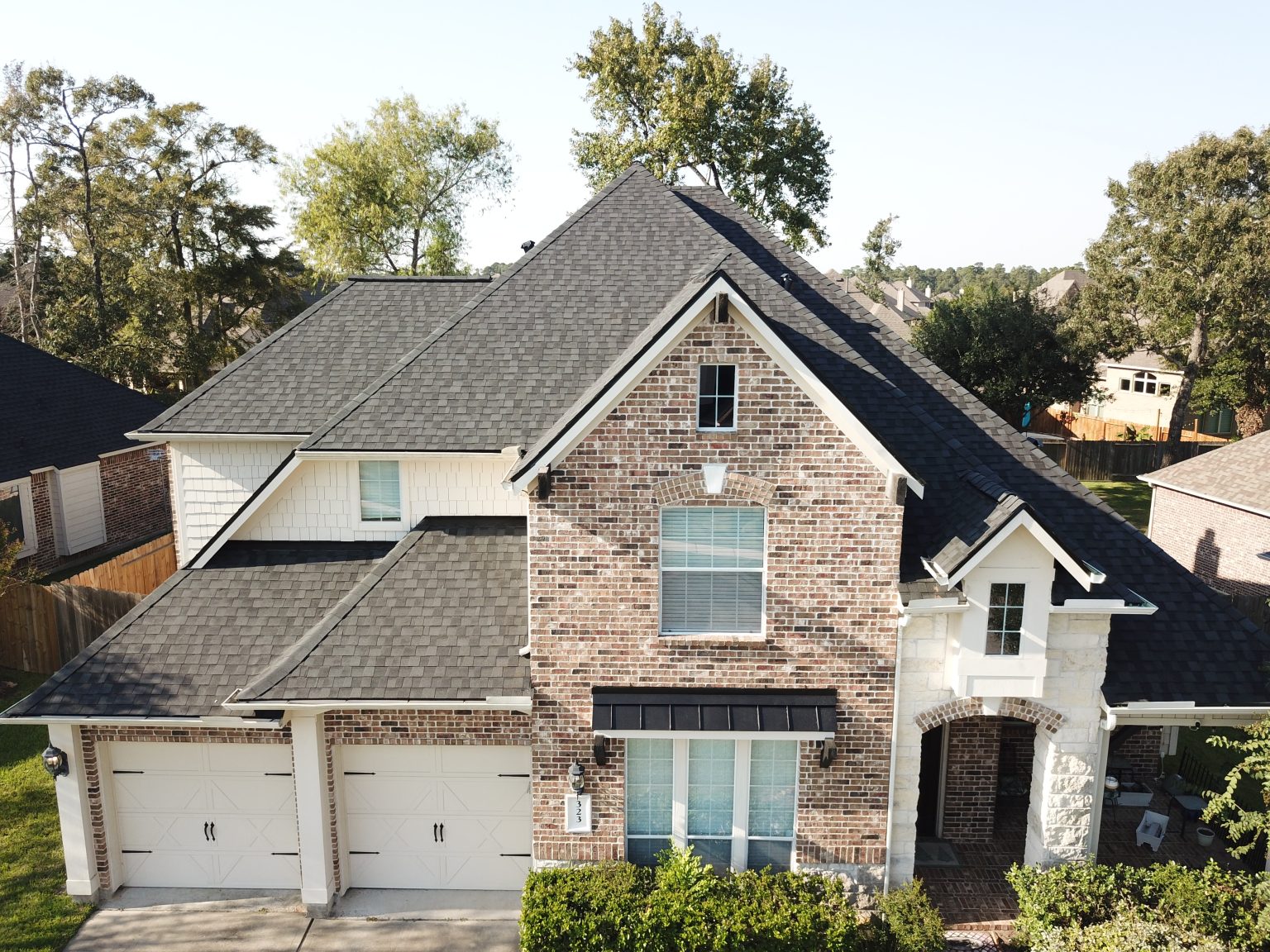 New architectural shingle roof on a two-story brick home, installed by Handnail Roofing