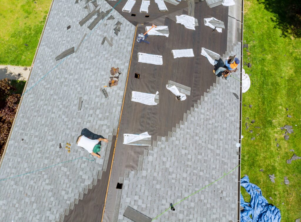 Roofer working on replacement asphalt shingle roof
